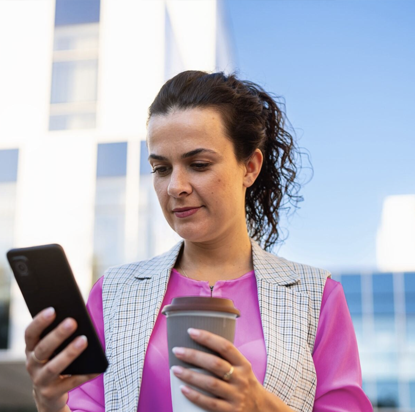 A woman drinking a coffee and holding a mobile phobe